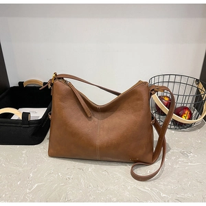 Detailed view of brown leather half-moon bag with elegant vertical stitching and logo