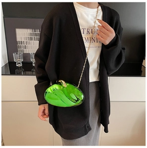 Neon green acrylic hard shell crossbody bag with elegant gold chain strap on model