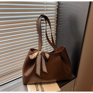 Detail of a large brown leather tote bag with a geometric print silk scarf handle