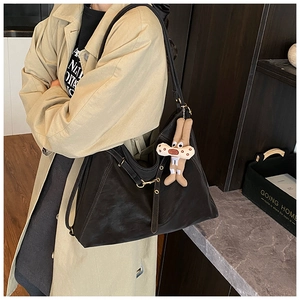 Detail of black leather tote bag with a cute beige rabbit plush keychain and gold hardware