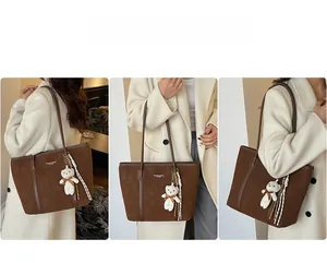 Detail view of large brown tote bag with plush bear charm and white printed text
