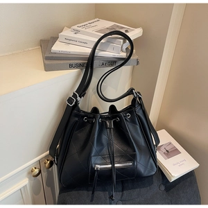 Détail du sac seau noir en cuir matelassé avec cordon de serrage et boucle argentée