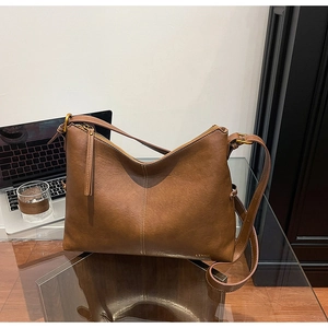 Detail view of brown leather hobo bag featuring LYSMH metal logo and vertical stitching