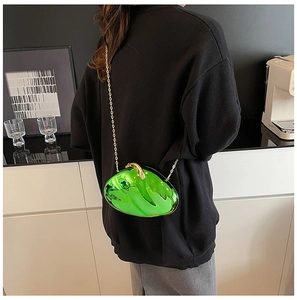 Detail of emerald green acrylic clutch bag with gold chain worn on shoulder