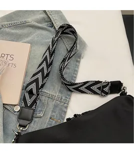 Detail view of the black canvas bag showing the adjustable geometric pattern wide strap