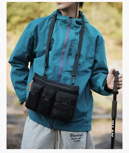 Close-up of black tactical crossbody bag with three functional pockets and orange pull tabs