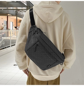 Gros plan sur le sac bandoulière à carreaux noir et blanc avec large sangle réglable