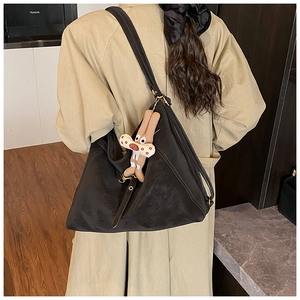 Close-up of black retro tote bag in matte leather featuring a brown plush cartoon pendant