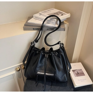 Gros plan du sac seau noir matelassé avec cordon et fermeture éclair sur une chaise