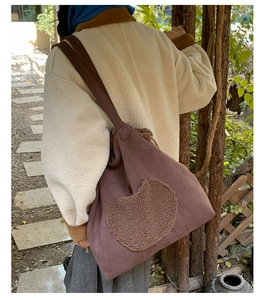 Close-up of brown suede tote bag with a soft faux shearling heart patch for autumn style