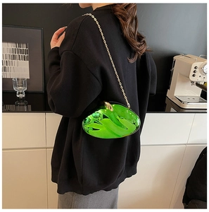 Detail of neon green acrylic clutch bag with gold handle and chain on a stylish model