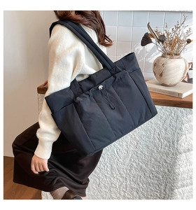 Détail du grand sac cabas noir avec bandoulière large et poches latérales utiles