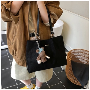 Detail of a large black tote bag with silver rings and a cute baseball bear charm