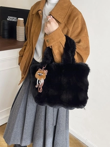 Grand sac cabas noir en fausse fourrure avec breloque léopard porté par un modèle