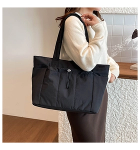 Détail du sac cabas noir avec poches latérales à cordon et tissu en nylon durable