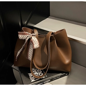 Detail of dark brown tote bag in matte leather featuring a geometric print silk scarf
