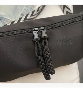 Detail of smooth double zipper closure with black woven pullers on nylon crossbody bag