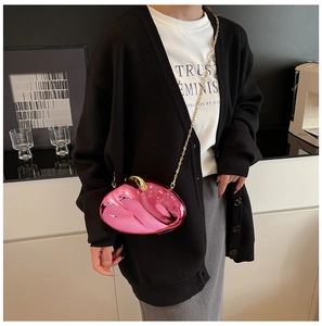 Detail of glossy pink acrylic evening clutch with gold chain strap on a model