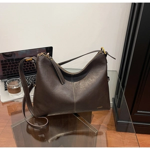 Detailed close-up of dark brown leather hobo bag featuring contrast stitching and logo