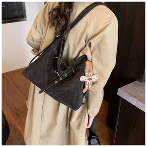 Detail of black PU leather tote bag featuring adjustable side buckles and rabbit charm