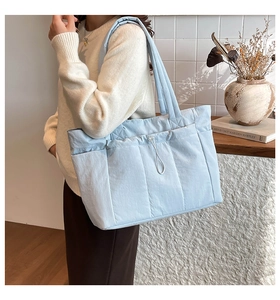 Grand sac fourre-tout bleu clair avec poches latérales porté à l'épaule chez soi