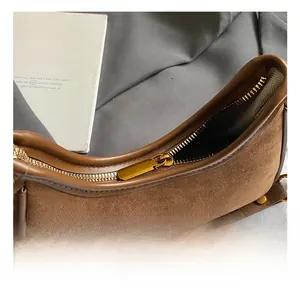 Detail of premium gold metal zipper and brown suede texture on this chic underarm bag