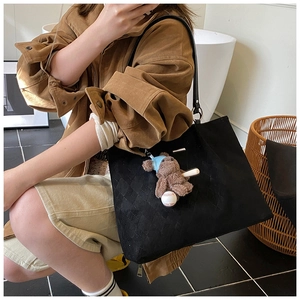 Quilted black tote bag detail featuring a cute teddy bear charm and soft leather straps