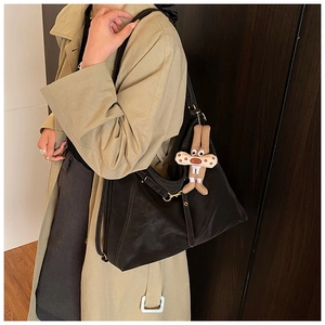 Detail of black faux leather tote with slim straps and a plush rabbit charm