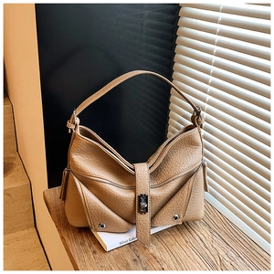 Detailed macro view of camel lychee pattern leather shoulder bag with metallic zipper accents