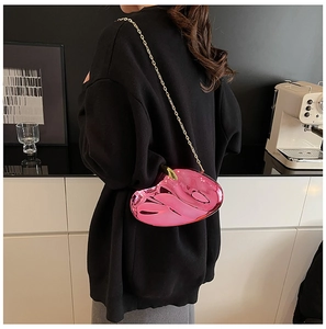Chic pink heart-shaped acrylic evening bag with gold chain strap on a model