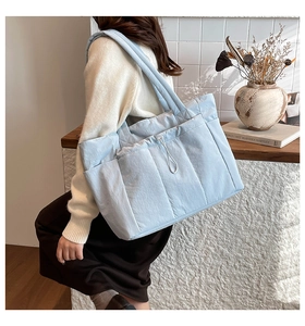 Détail du sac fourre-tout matelassé bleu clair montrant la poche latérale et le cordon