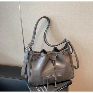 Détail du sac seau gris matelassé avec fermeture à cordon et garniture argentée