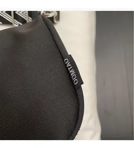Close-up of OOMTAO black nylon fabric bag with geometric woven strap and side brand label
