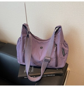 Détail du sac à bandoulière en nylon violet imperméable avec plusieurs poches zippées pratiques