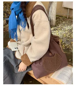 Brown suede tote bag with heart-shaped fleece patch shown in a winter outdoor setting