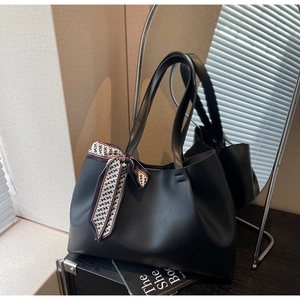 Close-up of black leather tote bag with stylish H-pattern silk scarf handle detail