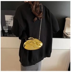 Close-up of a gold mirror-finish irregular clutch with a fine metal chain strap