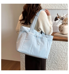 Détail du sac cabas matelassé bleu clair avec poche latérale et cordon de serrage