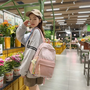 Pink star-patterned school backpack with cute yellow moon pendant and tassels worn by model