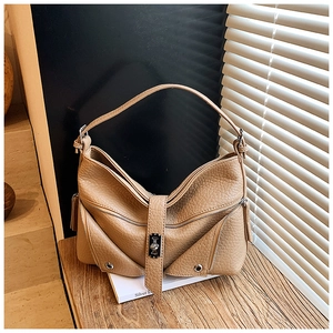 Close-up of brown textured leather shoulder bag with vintage metal turn-lock and zipper details