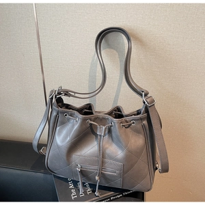 Gros plan du sac seau gris foncé avec motifs matelassés et détails de cordon de serrage
