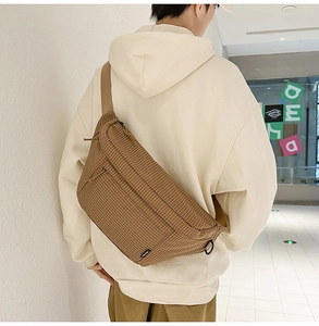Vue détaillée du sac bandoulière en nylon à carreaux marron porté sur un sweat à capuche