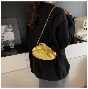 Close-up of golden metallic streamlined heart-shaped clutch bag with a slim chain strap