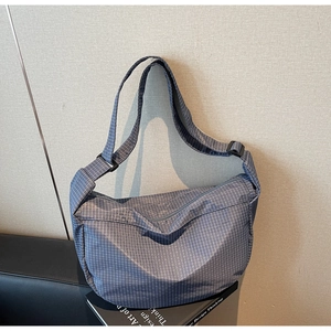 Dettaglio macro della borsa a tracolla a quadretti grigio-blu con tessuto e tracolla