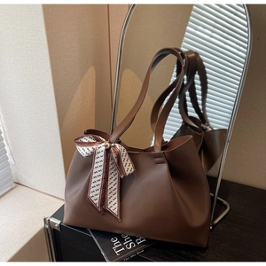 Detailed view of a brown tote bag featuring a decorative geometric print silk scarf handle