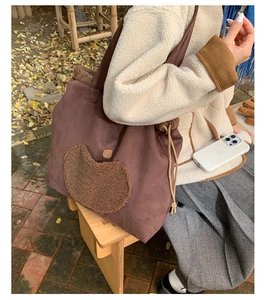 Detail of drawstring lamb wool tote bag with apple patch shown in outdoor setting