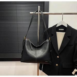 Detail showing high-gloss black tote bag with gold hardware and vertical stitching details