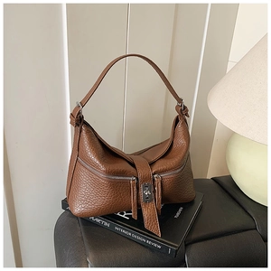 Detail view of brown pebbled leather texture and silver buckle on a hobo shoulder bag