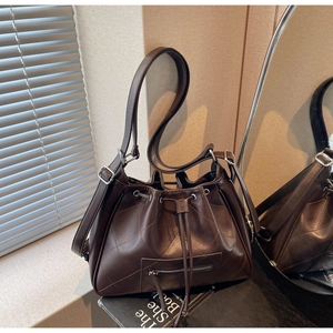 Vue détaillée du sac seau marron foncé en similicuir matelassé avec cordon et poche zippée