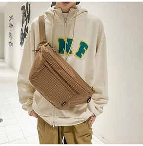 Détail du sac bandoulière en nylon à carreaux marron avec poches zippées et sangle ajustable